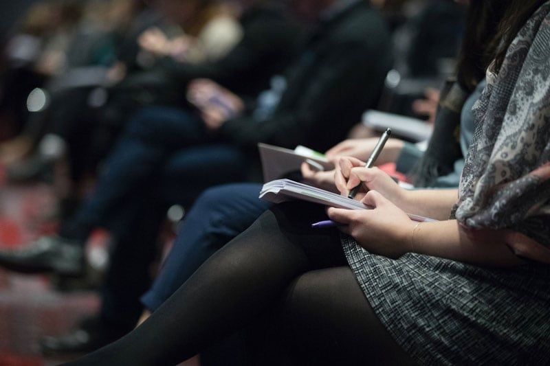 People sitting writing down notes a 